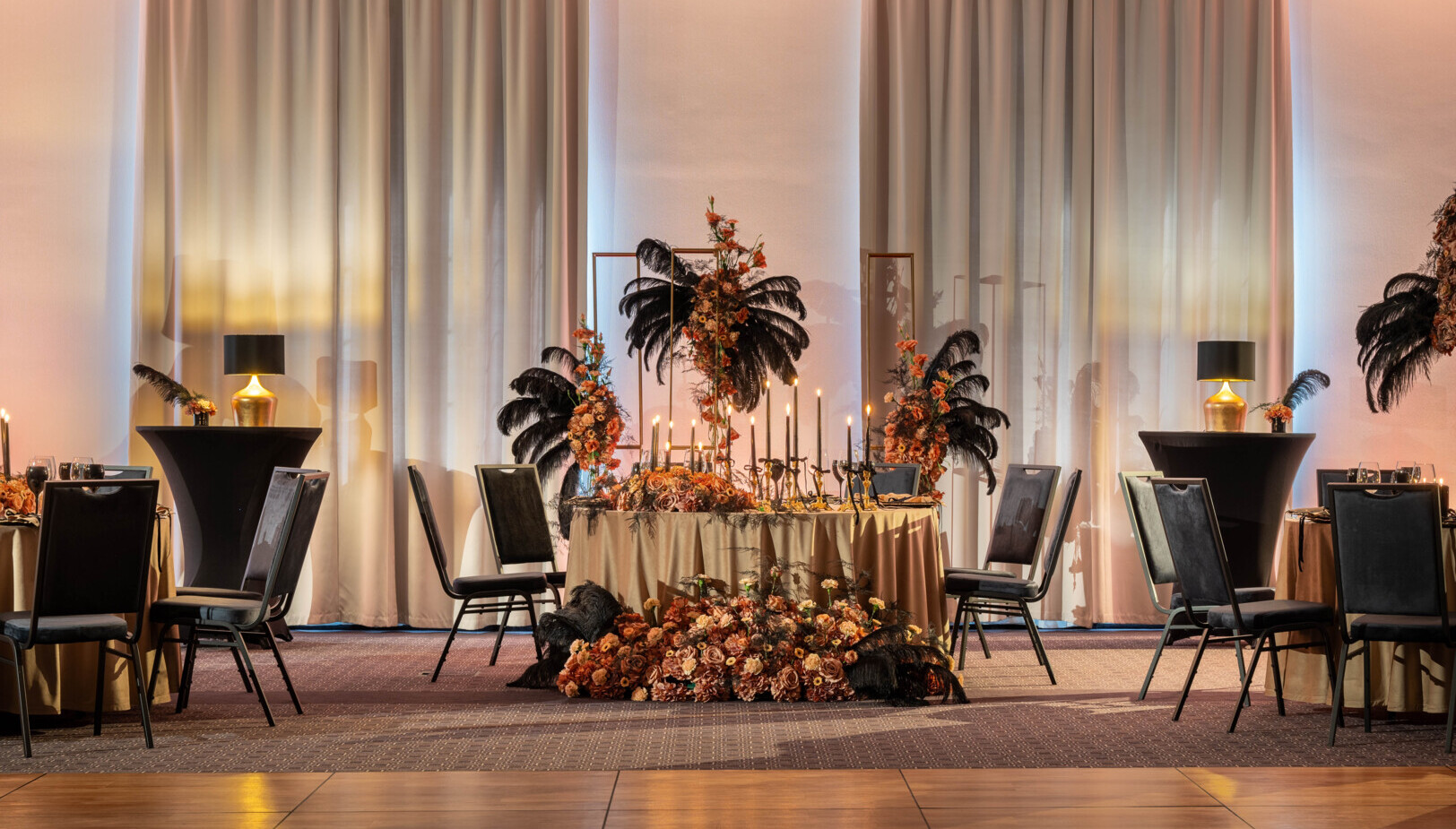 Elegancki stolik na sali bankietowej w stylu glamour ze świecami i kompozycją świeżych kwiatów