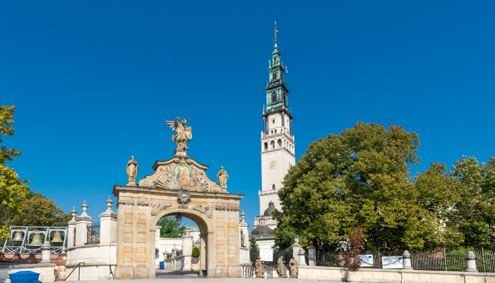 Zabytkowa brama wejściowa na placu oraz widok wierzy na Jasne Górze w tle