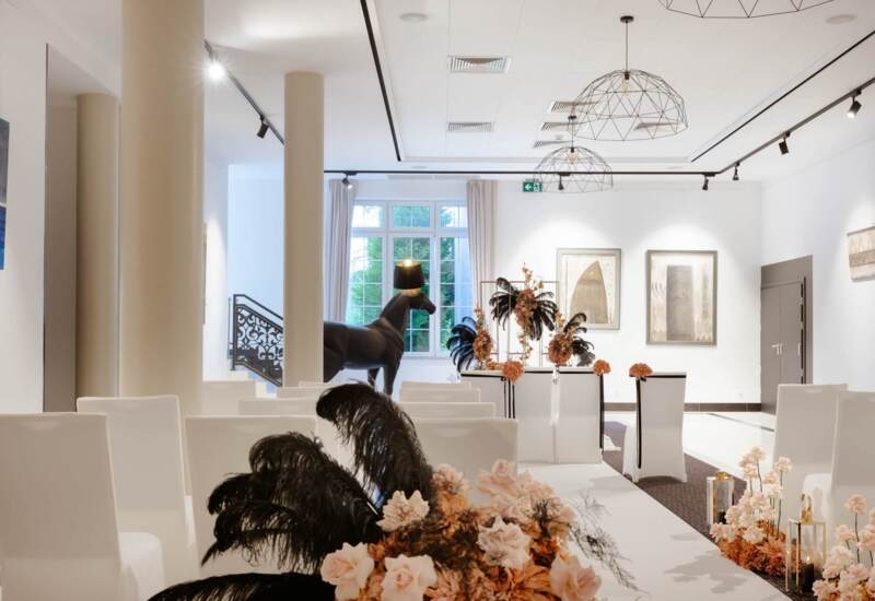 Elegancki jasny korytarz hotelowy, przyozdobiony świeżymi kwiatami z rzeźbą w tle