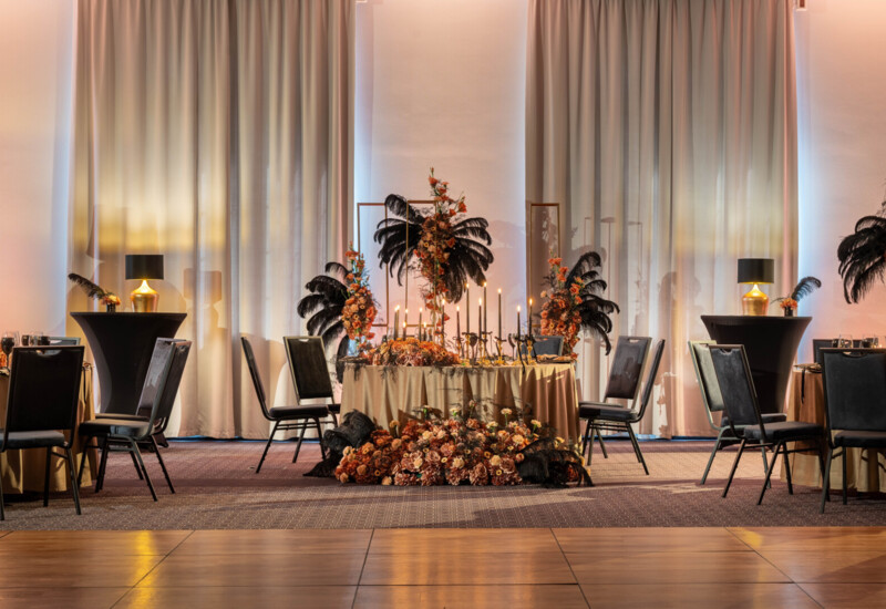 Elegancki stolik na sali bankietowej w stylu glamour ze świecami i kompozycją świeżych kwiatów