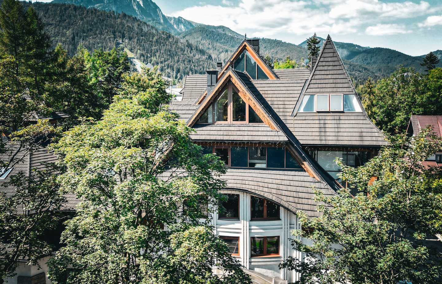شاليه فندقي جبلي بسقوف حادة على شكل A ونوافذ بإطارات خشبية وسط أشجار وإطلالة جبلية هادئة