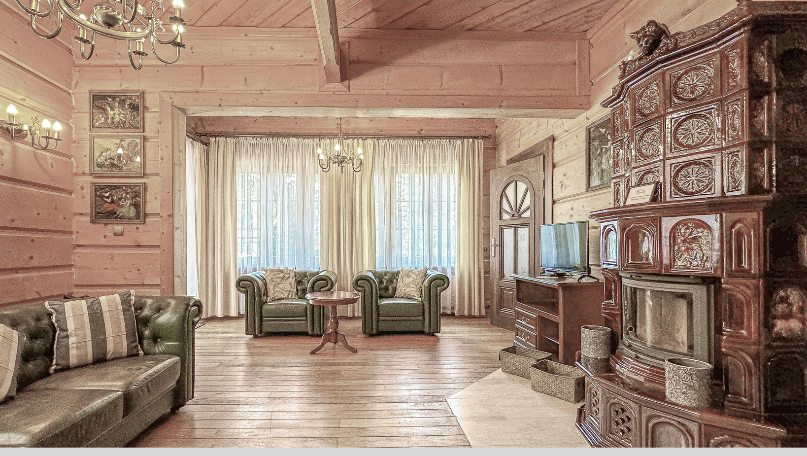 Przytulny salon w górskim stylu z zielonymi skórzanymi sofami, ozdobnym kaflowym piecem, drewnianymi belkami, żyrandolem i telewizorem