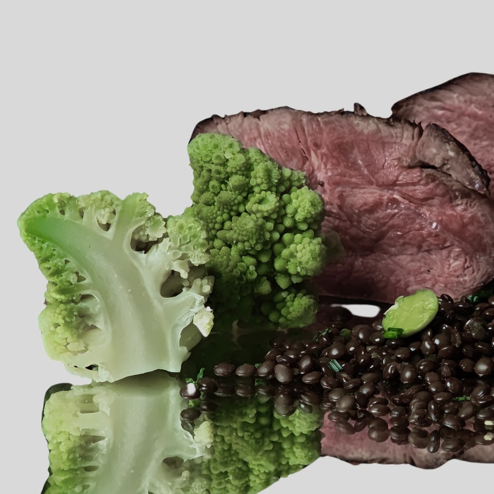 Plátky stredne prepečeného hovädzieho s čiernou šošovicou, bobom, rozmarínom a brokolicou romanesco na lesklom tanieri