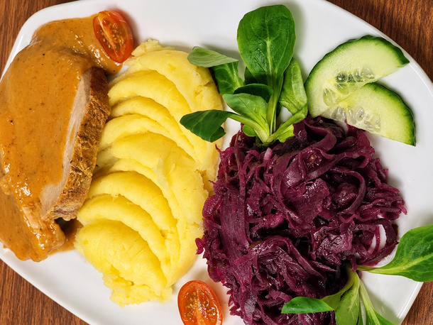 Plastry pieczonego mięsa w sosie z puszystym puree, duszoną czerwoną kapustą, świeżymi ogórkami i rukolą