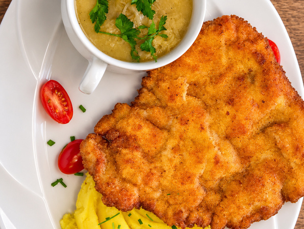 Chrupiący kotlet panierowany z kremowym puree, filiżanka sosu cebulowego z natką, pomidorki cherry i szczypiorek