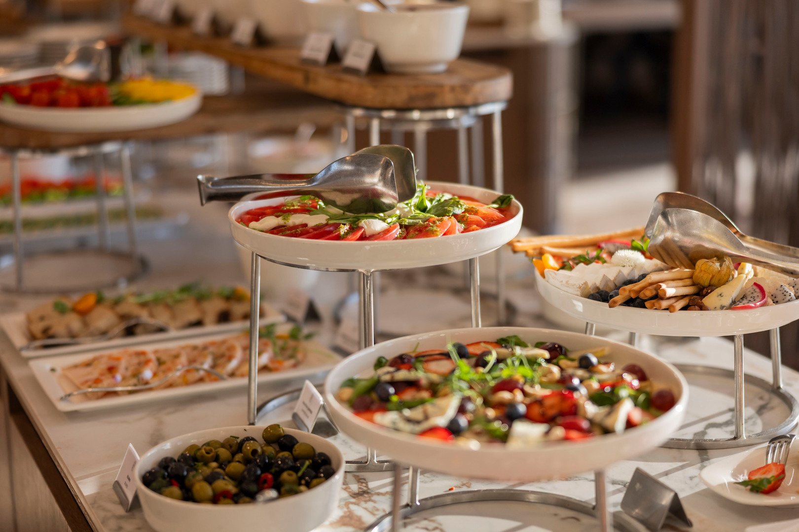 Mehrstöckiges Buffet mit frischem Caprese, gemischten Salaten, Oliven, Käse und Grissini auf einer Marmorplatte