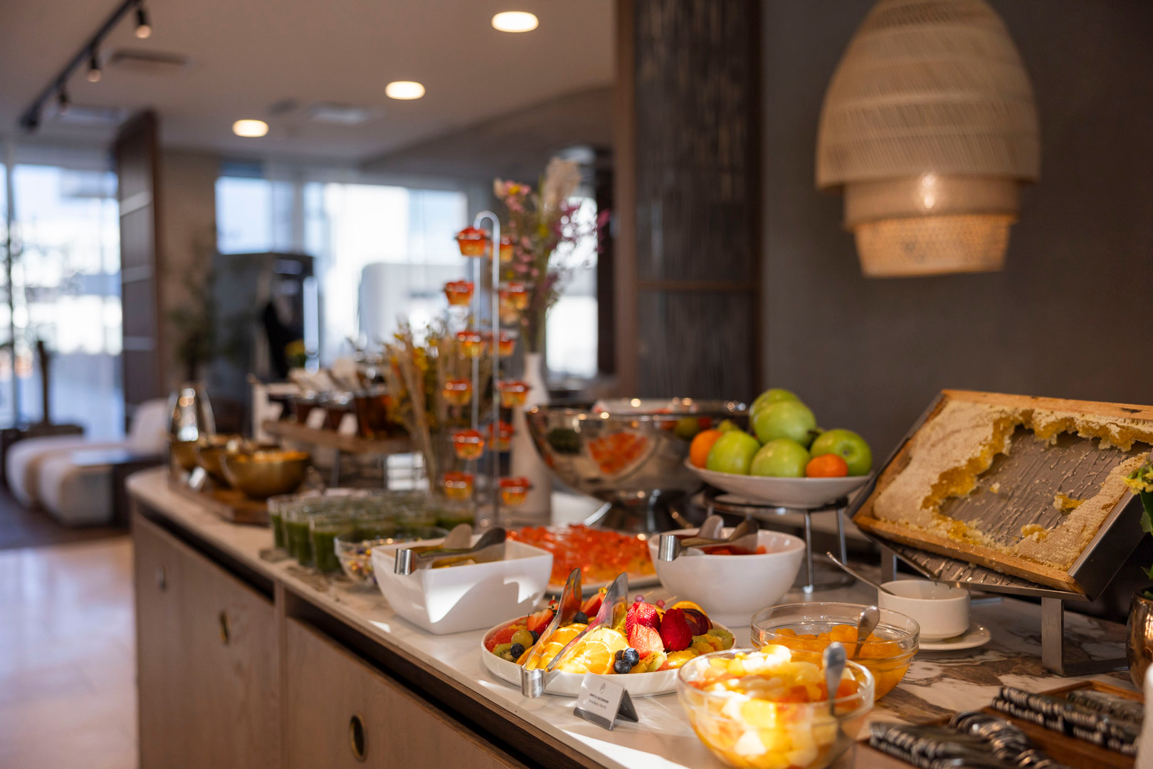 Hotel-Frühstücksbuffet mit frischem Obst, Honigwabe, Schalen mit Aufstrichen und warmem Ambiente