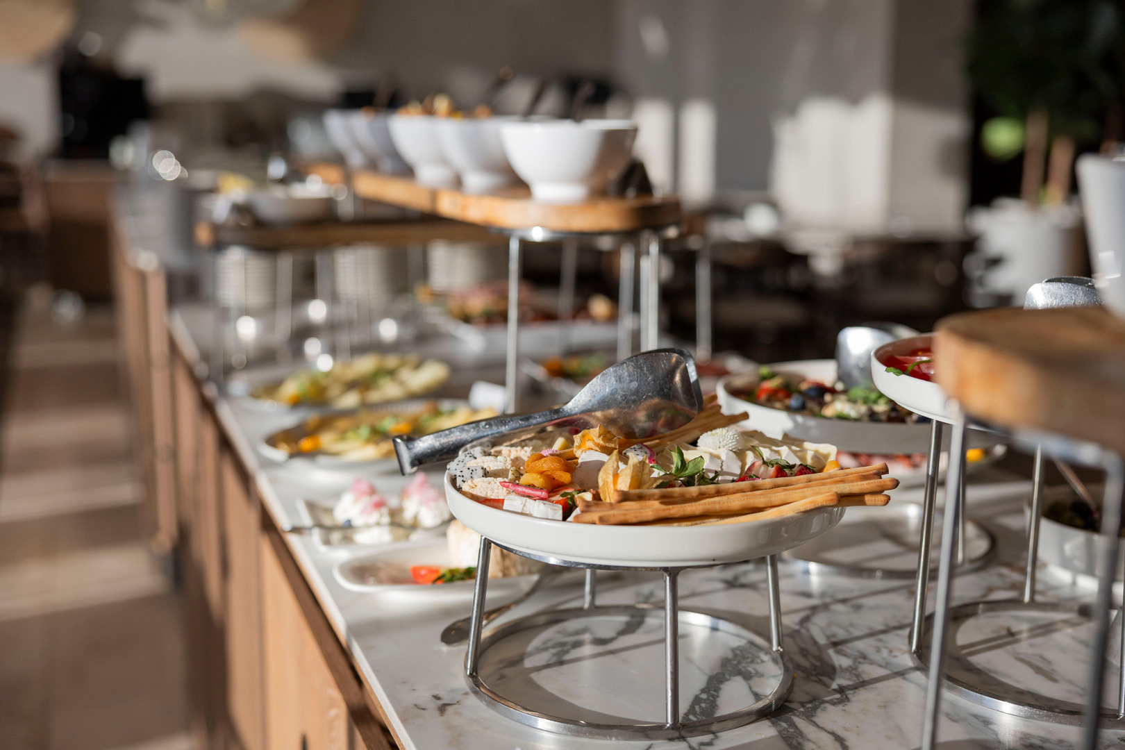 Hotel-Buffet mit Käse, Grissini, getrockneten Früchten und Schalen auf erhöhtem Marmortresen