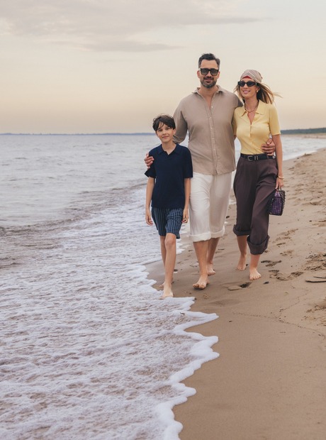Rodzina idąca boso po spokojnej piaszczystej plaży o zachodzie słońca