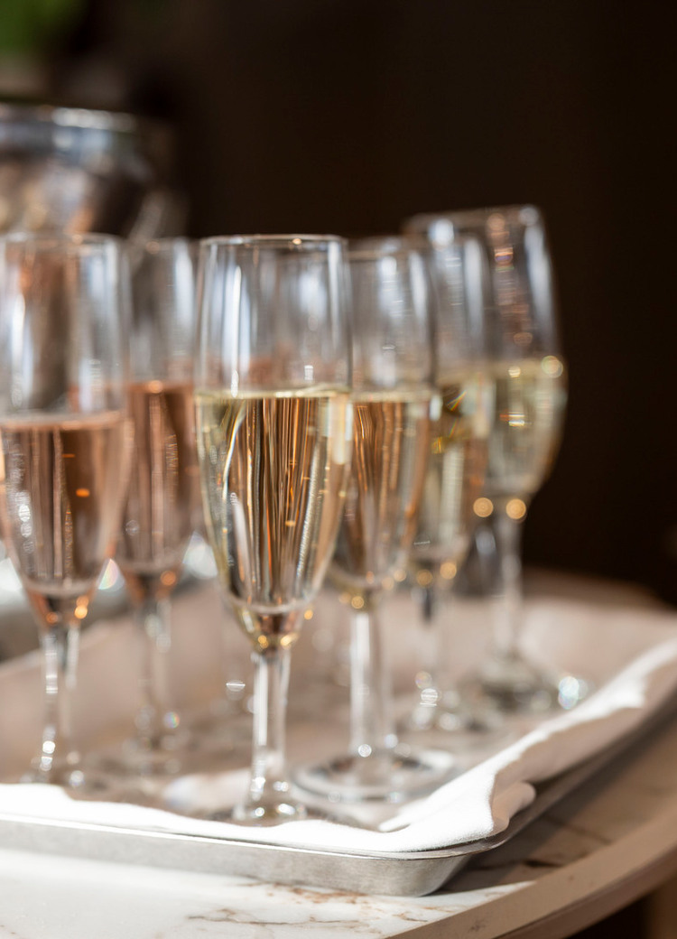 Musserende vin- og roséglass på hvitklede brett ved en sølv isbøtte på hotellets marmor velkomstbord