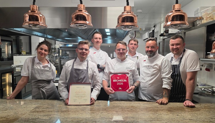 Zespół kuchni pod miedzianymi lampami trzyma z dumą tabliczkę Michelin 2026 i certyfikat