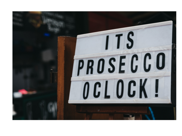 Podświetlana tablica z napisem 'It's Prosecco O'Clock!' w barze, zachęcająca oferta z złotą plakietką 'Best Seller'