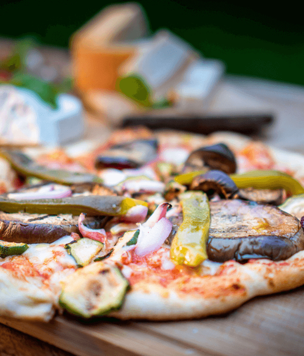 Pizza z pieca na drewnianej desce z grillowanym bakłażanem, cukinią, papryką i roztopionym serem