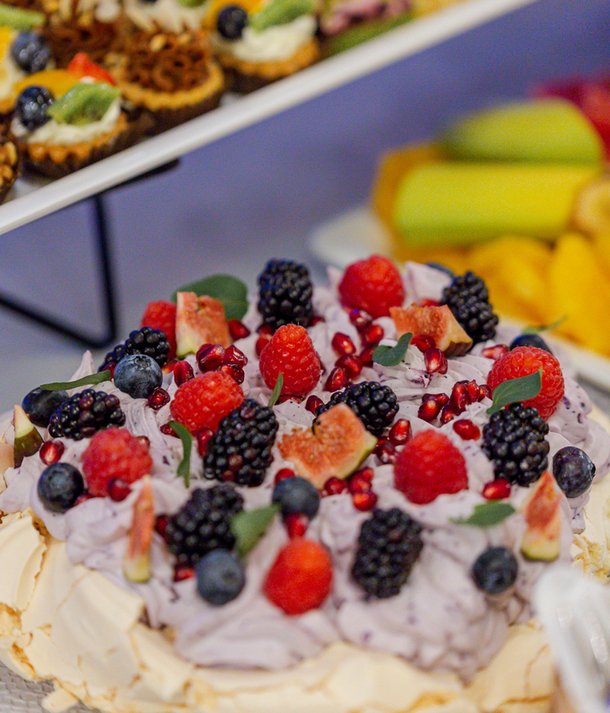Pavlova z jagodowym kremem, figami, malinami, jeżynami i pestkami granatu na hotelowym bufecie deserowym