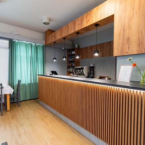 Modern breakfast bar with wooden slatted counter, pendant lamps, coffee machine, menu and flowers.