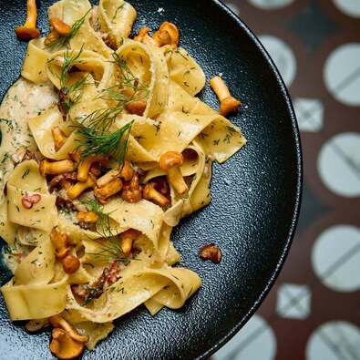 Kremowe pappardelle z kurkami, koperkiem i parmezanem, podane w czarnej misce