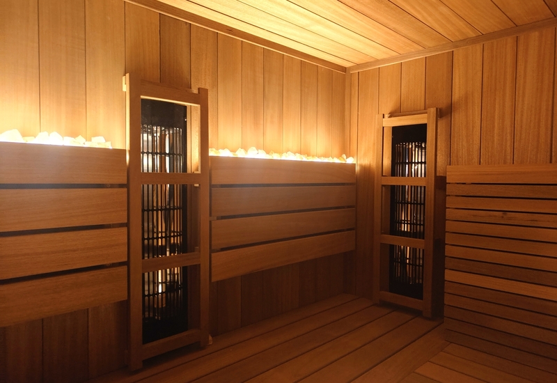 Sauna spa z drewnianymi ławkami, ciepłym nastrojowym oświetleniem i kamieniami grzewczymi na tylnej półce