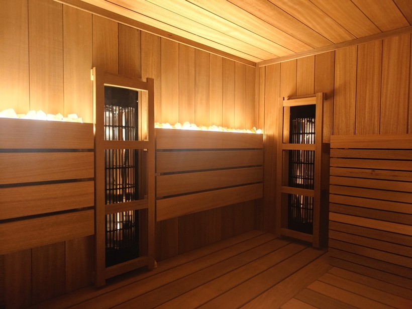 Sauna spa z drewnianymi ławkami, ciepłym nastrojowym oświetleniem i kamieniami grzewczymi na tylnej półce