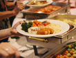 Hotelbuffet, Gäste bedienen sich an Tellern mit Kartoffelpüree, panierten Kroketten, Brokkoli, Karotten und Fleisch in Sauce