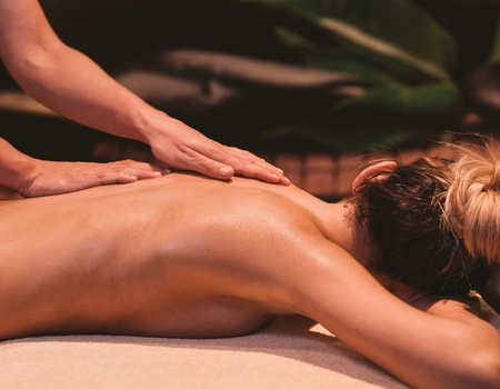 Relaksujący masaż pleców w spokojnym spa hotelowym z naturalnym oświetleniem i roślinną dekoracją