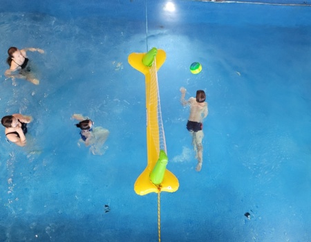 Gäste spielen Wasser-Volleyball mit einem aufblasbaren Netz im hoteleigenen Hallenbad
