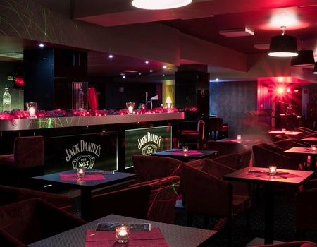 Stylový hotelový bar s červeným osvětlením, pohodlnými křesly a svíčkami na stolech pro hosty