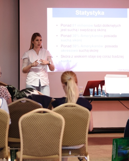 Konferenzraum mit Vortragender, die Hautpflege-Statistiken vor sitzenden Teilnehmern präsentiert