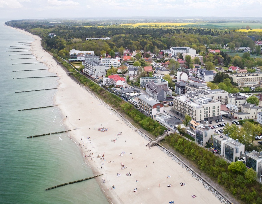 Breiter Sandstrand mit Gästen, moderne Hotels und Gebäude entlang der Küste mit Meerblick.