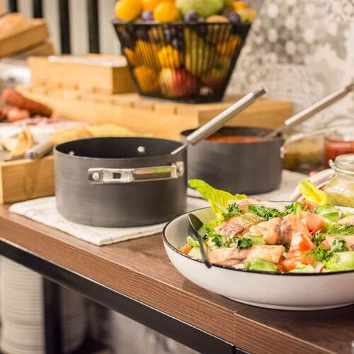 Stół bufetowy z sałatką z grillowanym łososiem, garnkami z sosami, chlebem i koszem świeżych owoców