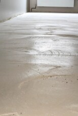 Unfinished hotel room floor with smoothing marks and neutral walls, under renovation for updated guest accommodations