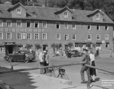Historisches Hotel Hessischer Hof mit klassischen Autos und Gästen in zeittypischer Kleidung auf ruhigem Stadtplatz