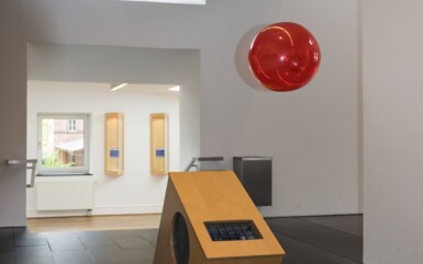 Moderner minimalistischer Hotellobby mit hellholzerner Rezeption, dunklen Fliesenboden und hellem Tageslicht durch hohe Fenster