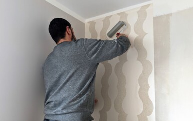Hotel staff applying modern beige wallpaper with a textured wave pattern in a guest room for a fresh updated look