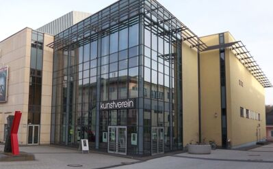 Moderner Kulturzentrum mit Glasfassade und beigen Wänden, Kunstwerke und Skulpturen auf großem Platz