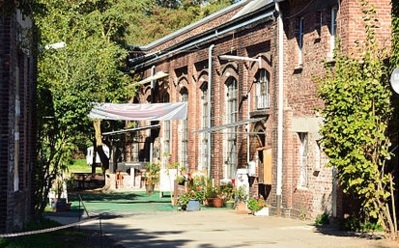 Sonniger Innenhof mit historischen Backsteingebäuden, Bögenfenstern, Grünflächen und Sitzbereichen zum Entspannen