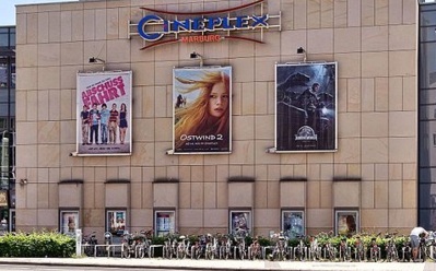 Modernes Kinogebäude mit großen Filmplakaten, Fahrradständern davor und sauberer urbaner Umgebung