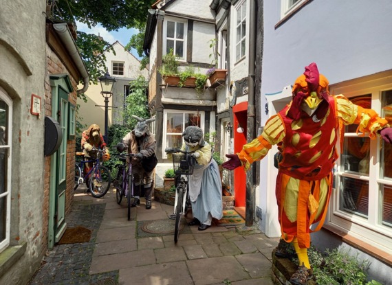 Charmante schmale Kopfsteinpflastergasse mit Fachwerkhäusern und lebensgroßen Tierfiguren mit Fahrrädern