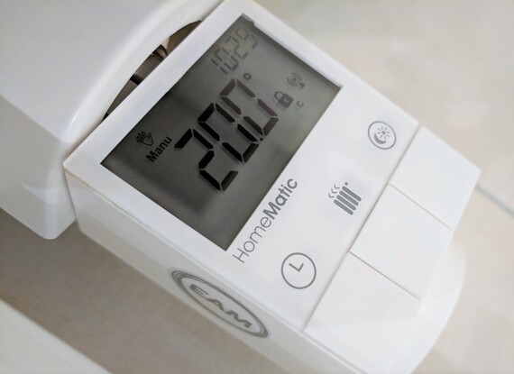 Nahaufnahme eines Raumthermostats, eingestellt auf 20°C mit manueller Steuerung und Heizungsanzeige