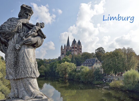 Historische Statue blickt auf Fluss mit grünen Bäumen und die markante Limburger Kathedrale auf einem Hügel unter leicht bewölktem Himmel