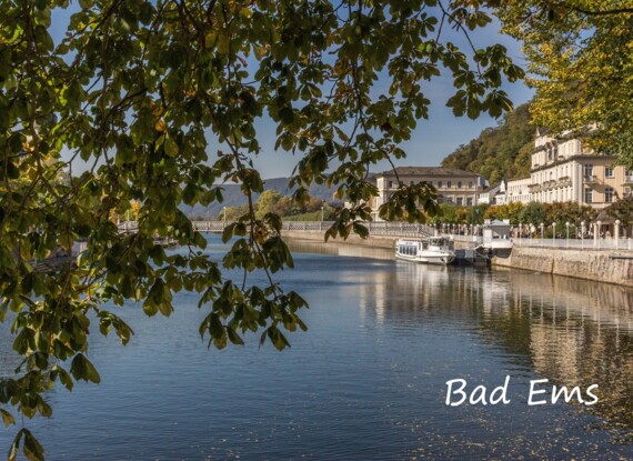 Historische Kurstadt Bad Ems mit klassizistischen Gebäuden am Flussufer, Ausflugsboot am Steg und von Bäumen gesäumtem Wasser