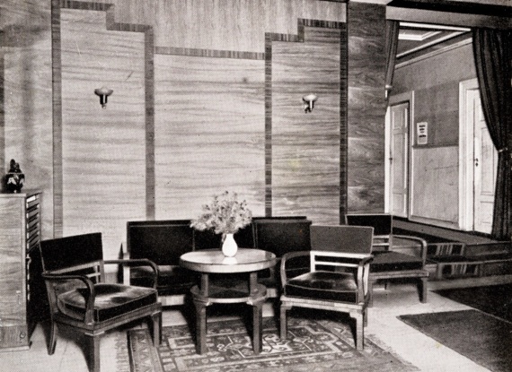 Gemütlicher Hotellobby-Bereich mit dunkelholzmöbeln, runder Tisch mit Vase und frischen Blumen im Zentrum