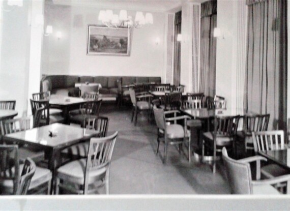 Gemütlicher Speiseraum im Hotel mit Holztischen und -stühlen, weichen Wandlampen und großer gepolsterter Sitzbank an der Wand