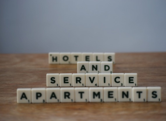 Scrabble-Buchstabenwürfel auf Holztisch mit der Aufschrift ‚HOTELS UND SERVICE APARTMENTS‘