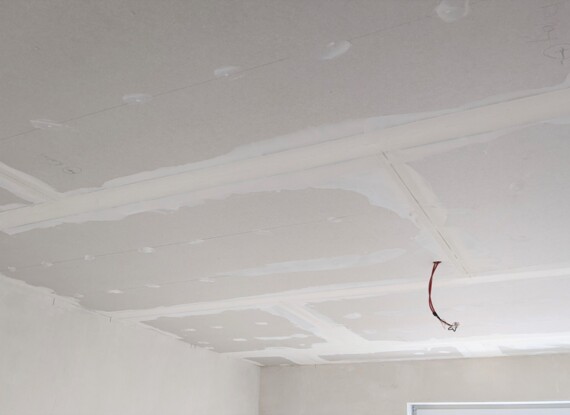 Unfinished ceiling with visible drywall panels and joint compound in a hotel room under construction