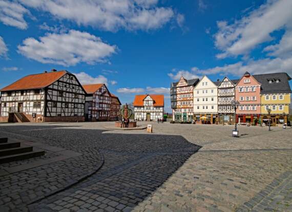 Historischer Marktplatz mit reizvollen Fachwerkhäusern, Kopfsteinpflaster und Straßencafés unter klarem blauem Himmel
