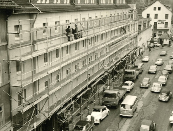 Historisches Hotelgebäude wird renoviert mit Gerüst an der Fassade und Oldtimer-Pkw, die an der Straße parken