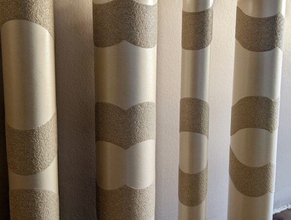 Close-up of textured beige and cream decorative columns with wave-like patterns in a softly lit interior space