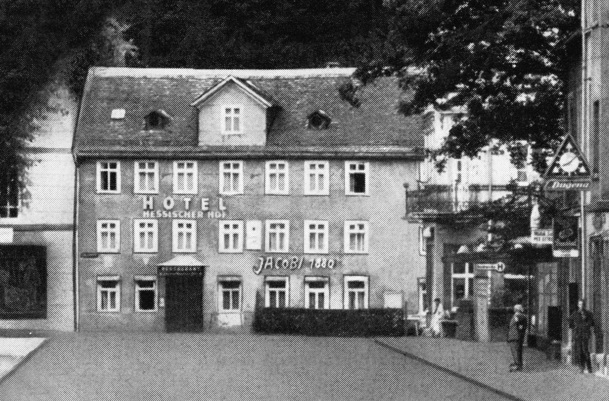 Historisches dreistöckiges Hotelgebäude mit mehreren weißgerahmten Fenstern und Satteldach an einer ruhigen Straßenecke