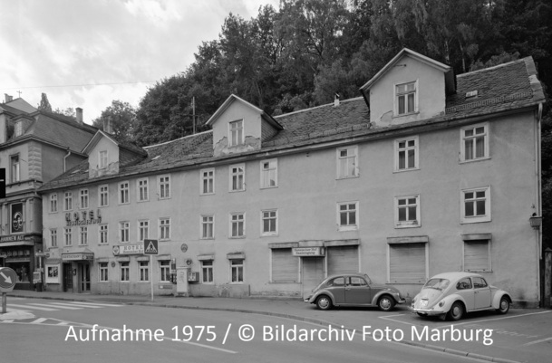 Historisches dreistöckiges Hotel mit vintage Fassade und Gaubenfenstern, an ruhiger Straße mit geparkten Oldtimern