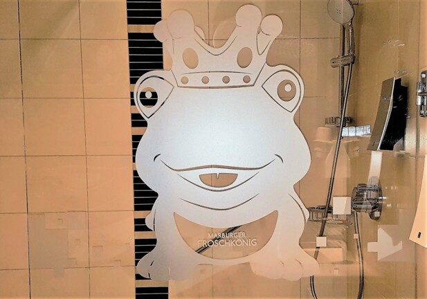 Dusche mit modernen Armaturen und satiniertem Glas mit einem verspielten Frosch mit Krone